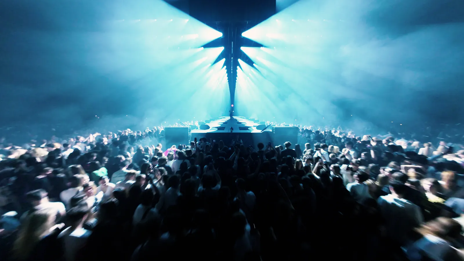 An arena crowd under blue stage beams: a frame from the OG Buda live edit